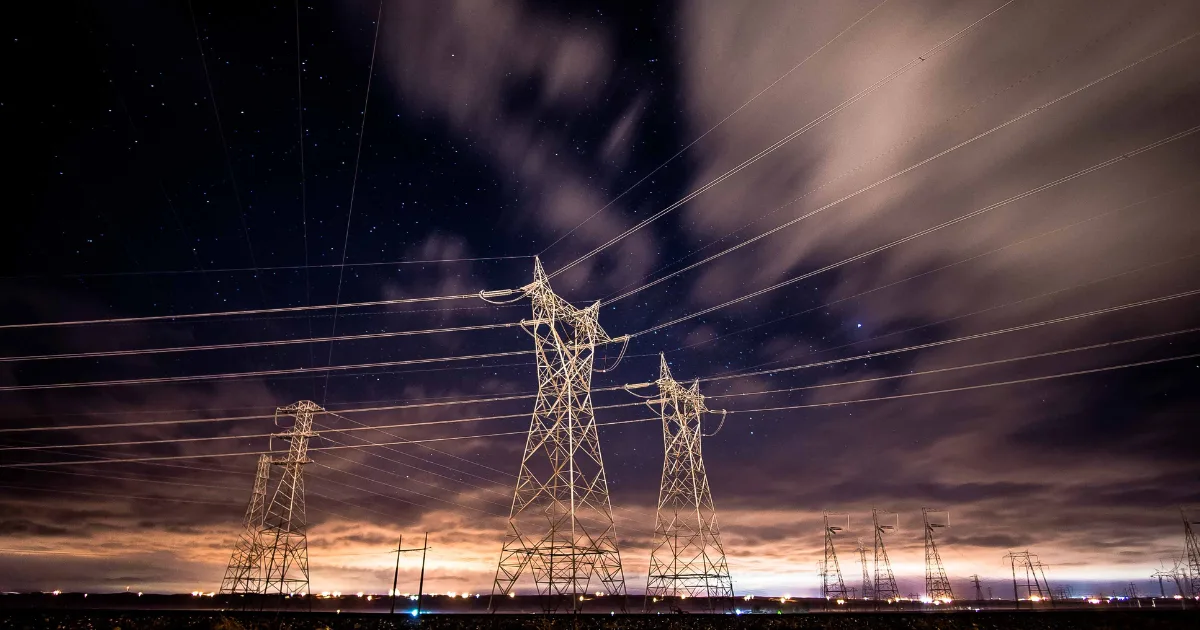 夜空に伸びる送電鉄塔と電線、雨雲が流れる様子のシンプルなイメージ